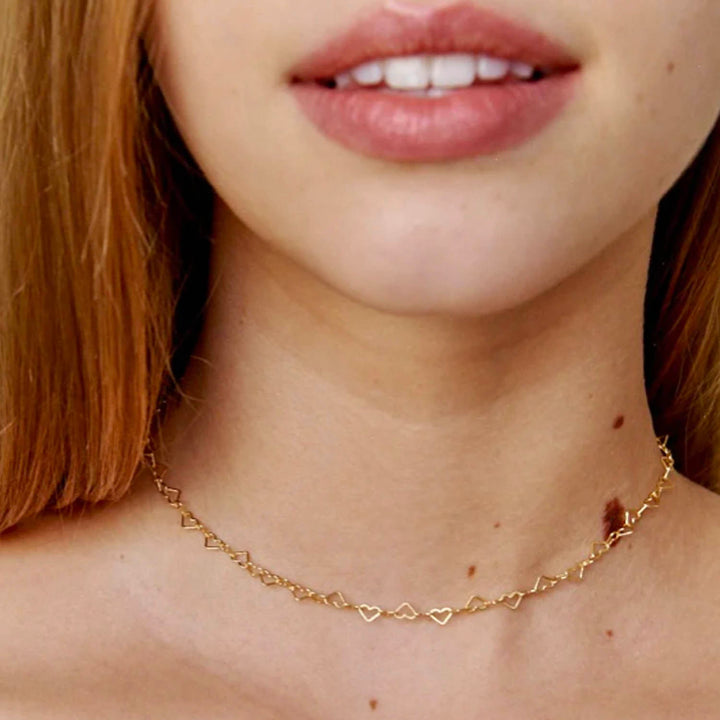 Modelo sonriendo con cadena de eslabones en forma de corazon - GOLD SHIELD