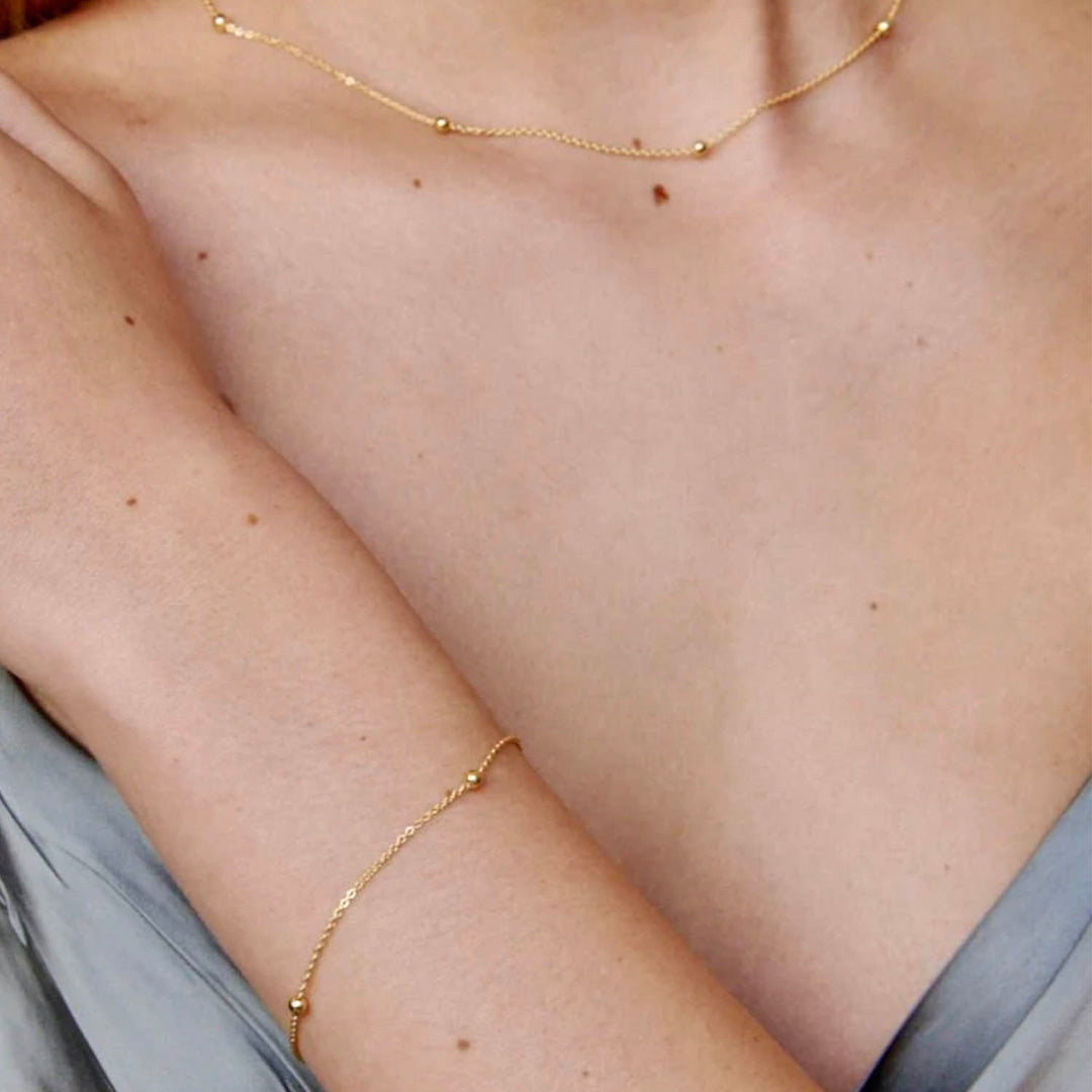 Modelo con pulsera y collar de oro - GOLD SHIELD