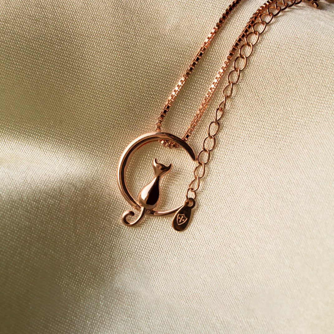 cadena de plata con colgante de gato en fondo color crema